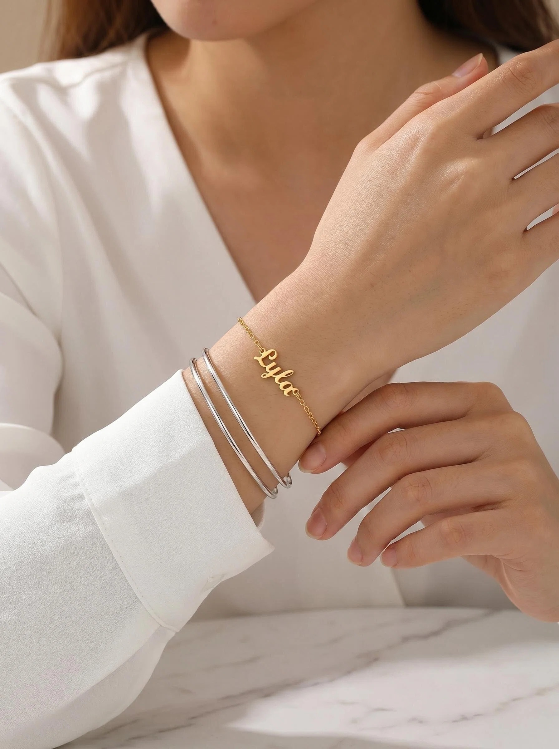 Custom name bracelet mixed with silver bangle — personalized warm-toned piece as anchor in mixed metals look